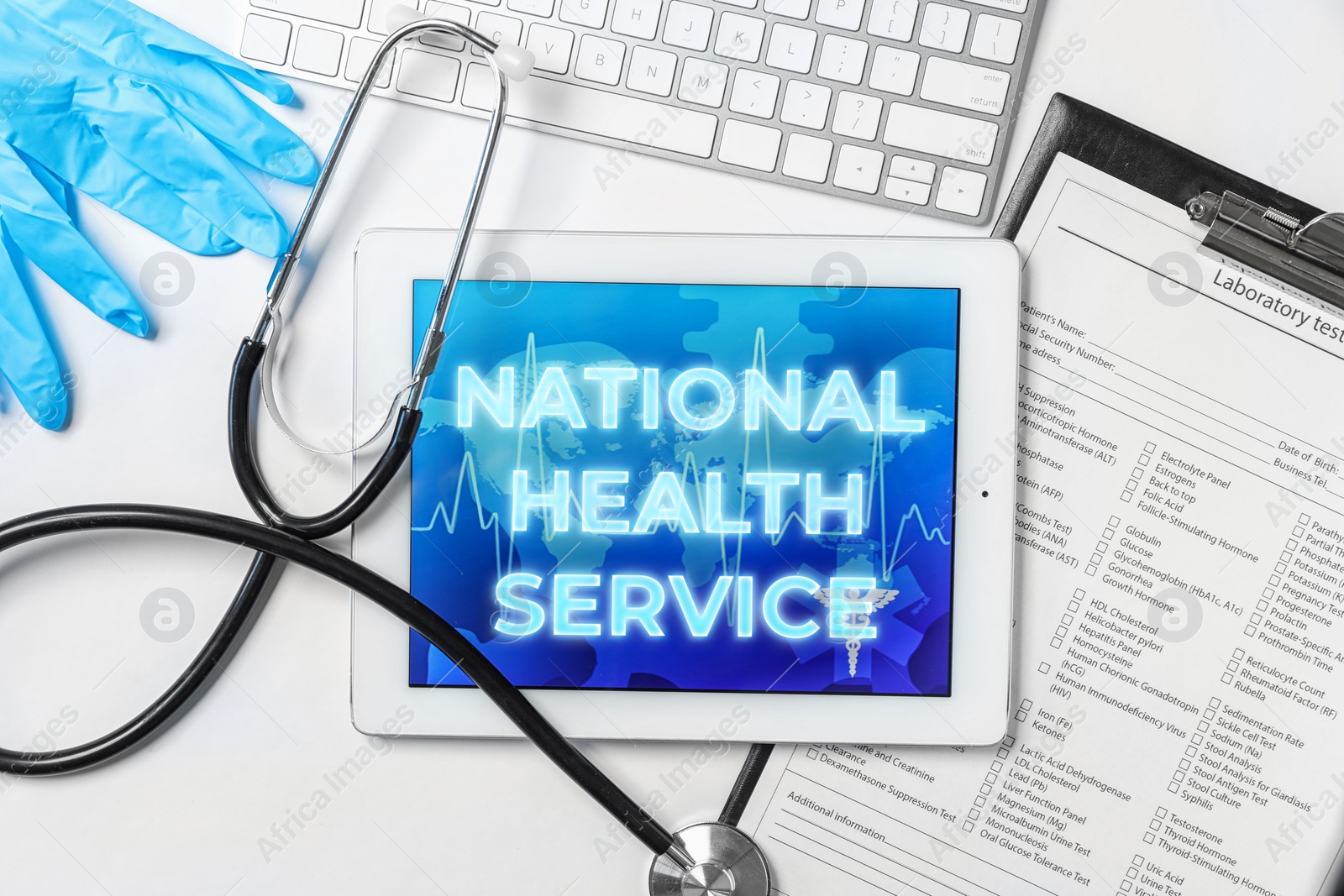 Image of National health service (NHS). Tablet with text, stethoscope, text form, gloves and keyboard on white background, flat lay