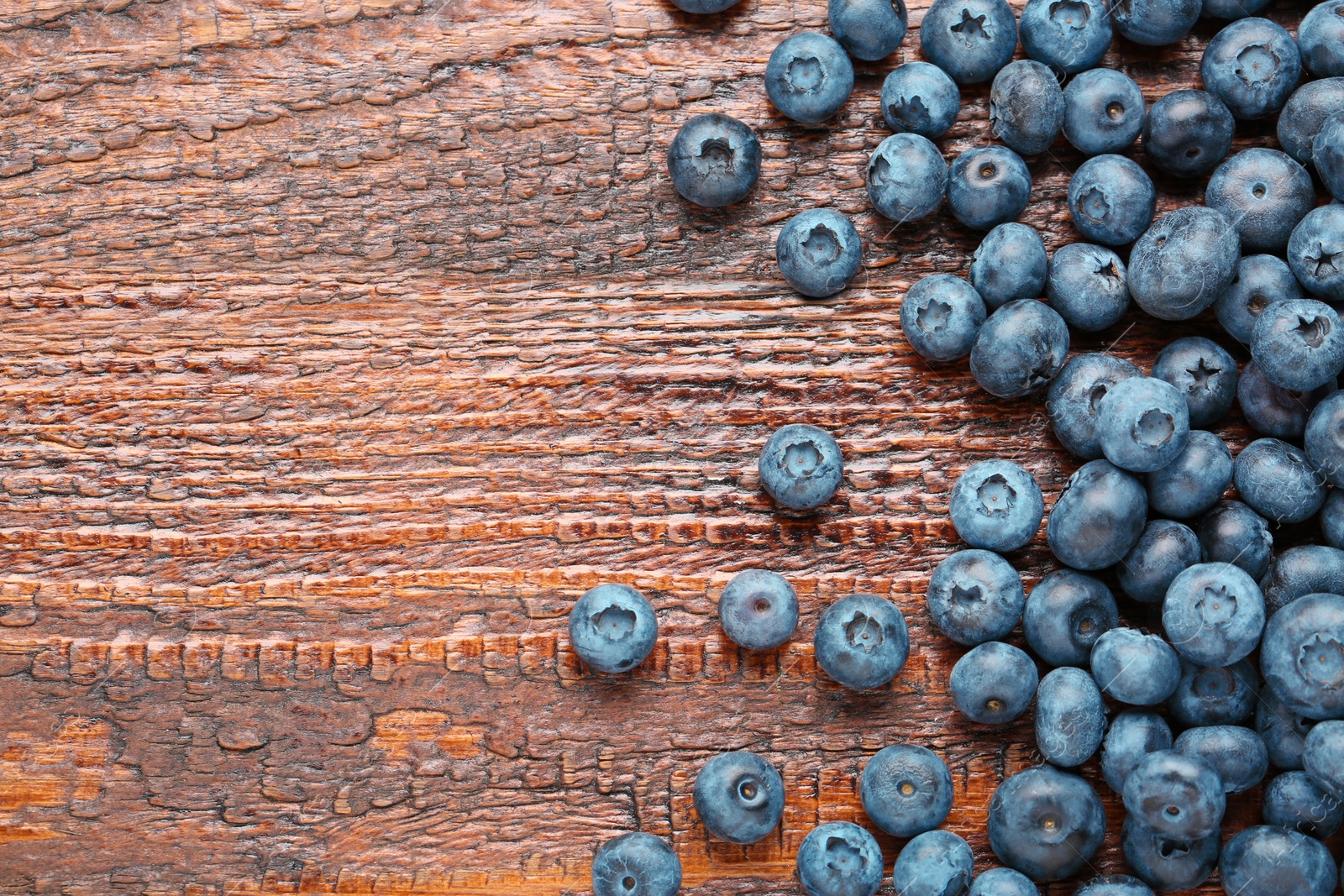 Photo of Tasty fresh blueberries on wooden table, flat lay. Space for text