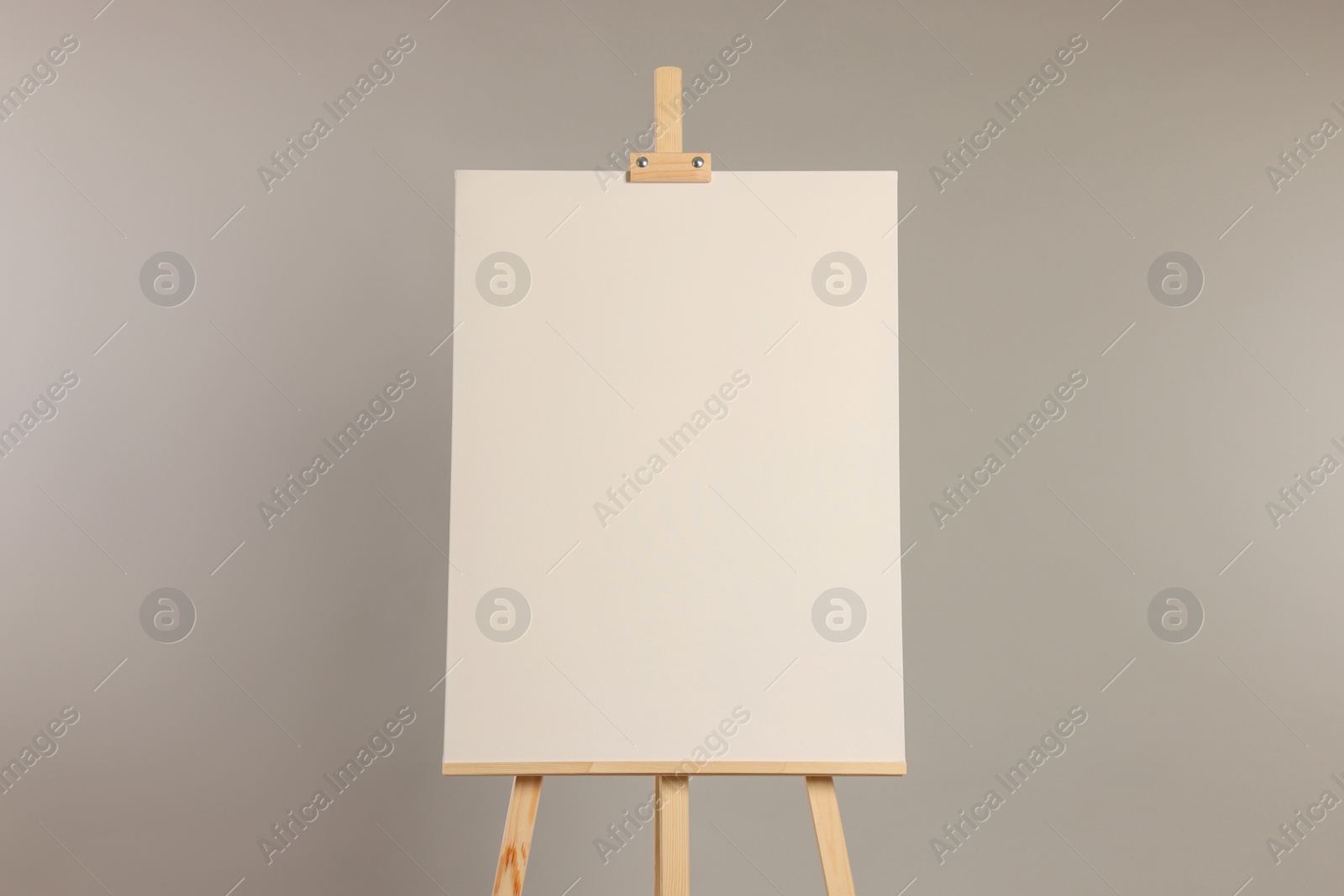 Photo of Wooden easel with blank canvas on grey background