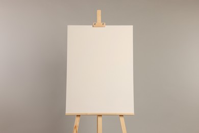 Wooden easel with blank canvas on grey background