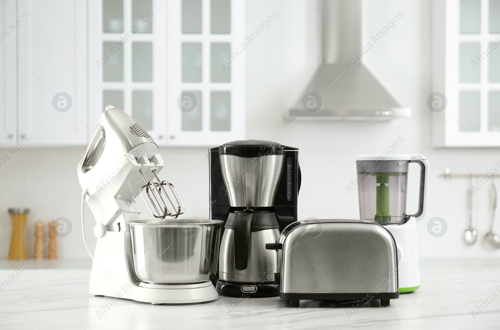 Photo of Modern toaster and other home appliances on white marble table in kitchen