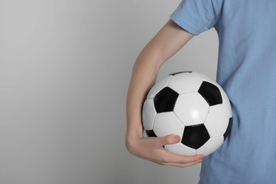 Boy with soccer ball on light grey background, closeup. Space for text