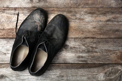 Photo of Dirty shoes and space for text on wooden background, top view. Poverty concept