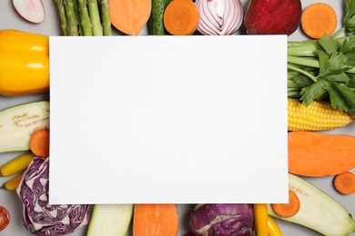 Flat lay composition with fresh vegetables and blank card for text on gray background