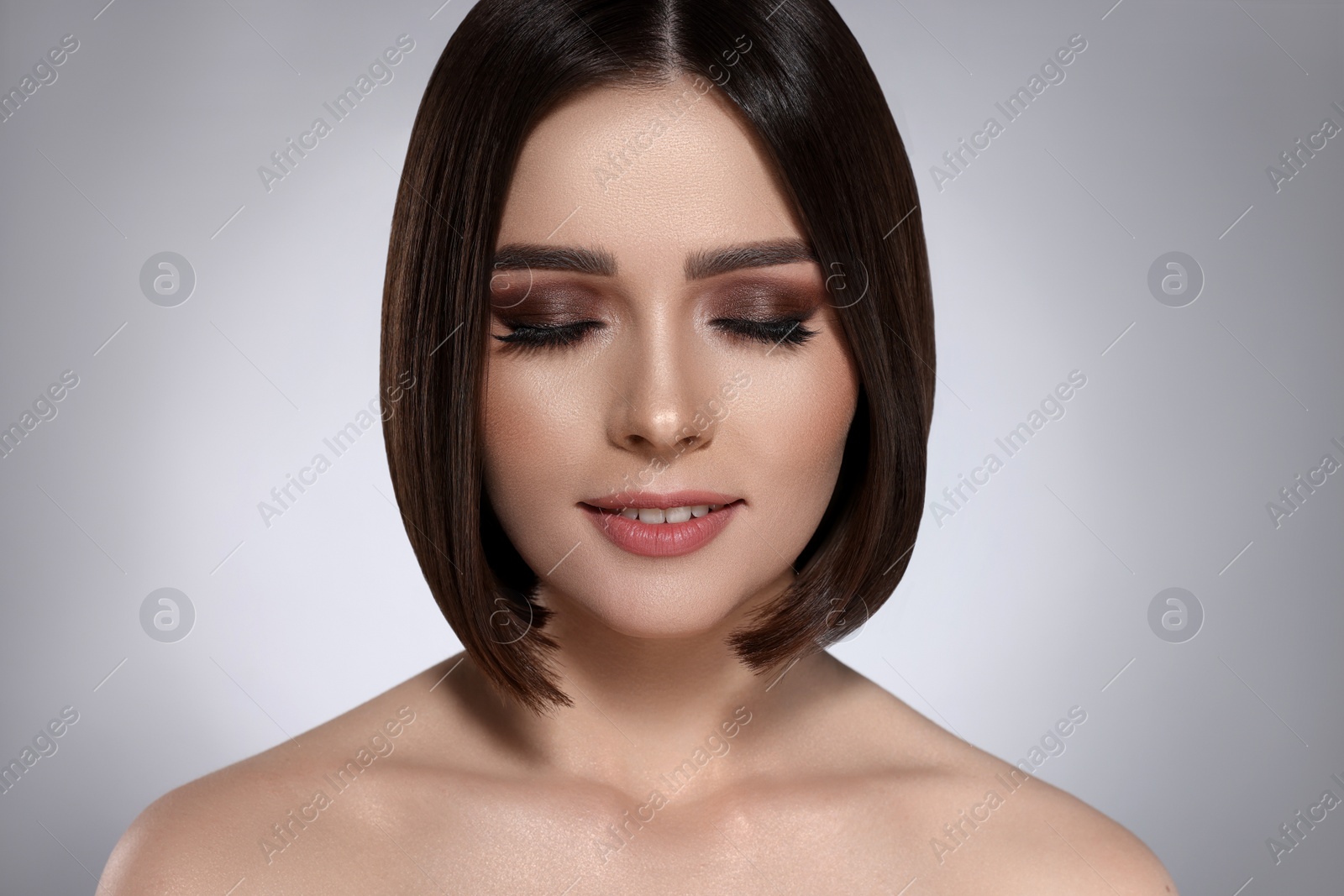 Image of Portrait of pretty young woman with brown hair on grey background