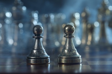 Pawns in front of chess pieces on checkerboard, selective focus