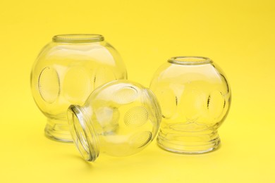 Photo of Glass cups on yellow background, closeup. Cupping therapy