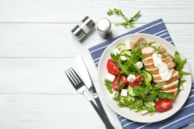 Delicious salad with chicken, arugula and tomatoes on white wooden table, flat lay. Space for text