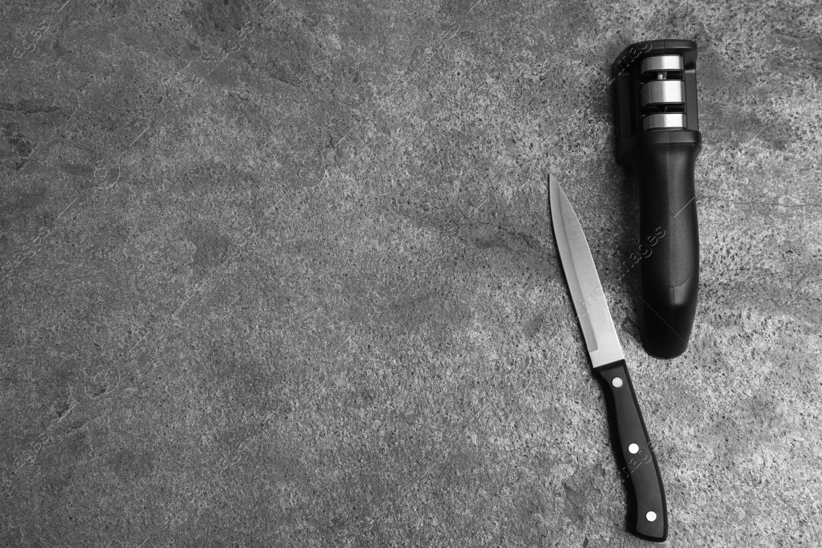 Photo of Modern handheld sharpener and knife on grey table, flat lay. Space for text