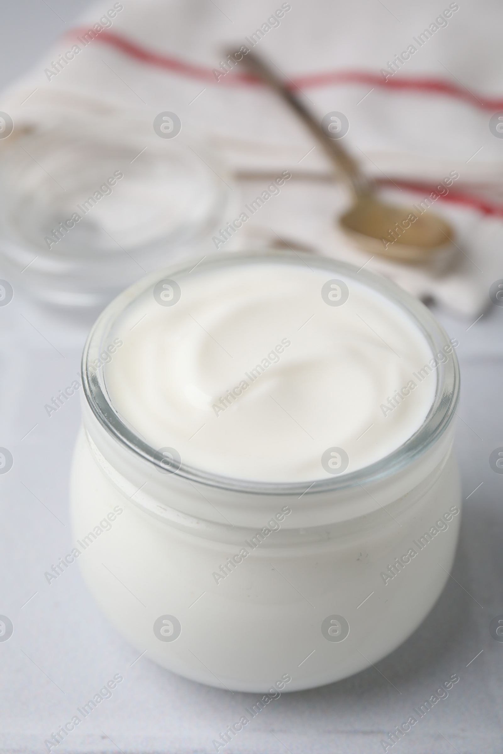 Photo of Delicious natural yogurt in glass jar on white table, closeup