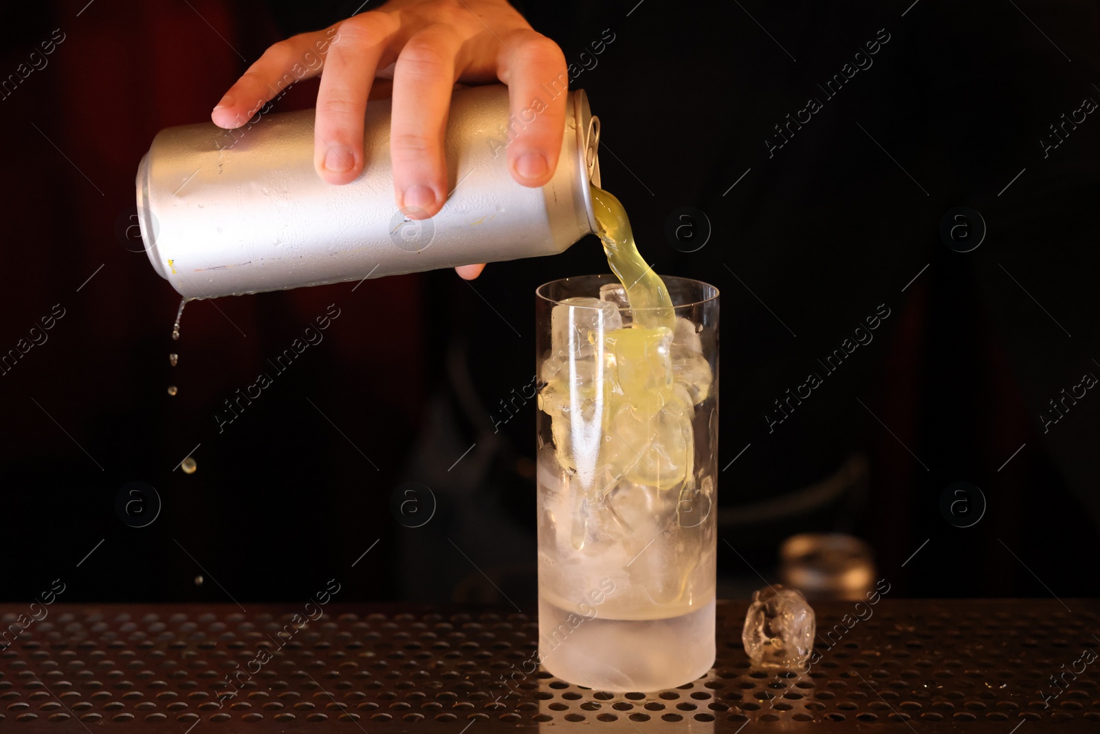 Photo of Bartender pouring energy drink into glass at counter in bar, closeup