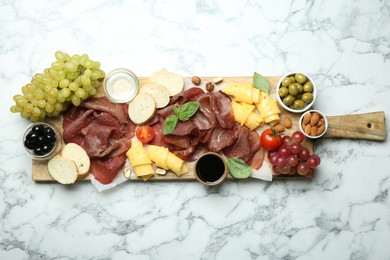 Photo of Charcuterie board. Delicious bresaola and other snacks on white marble table, top view