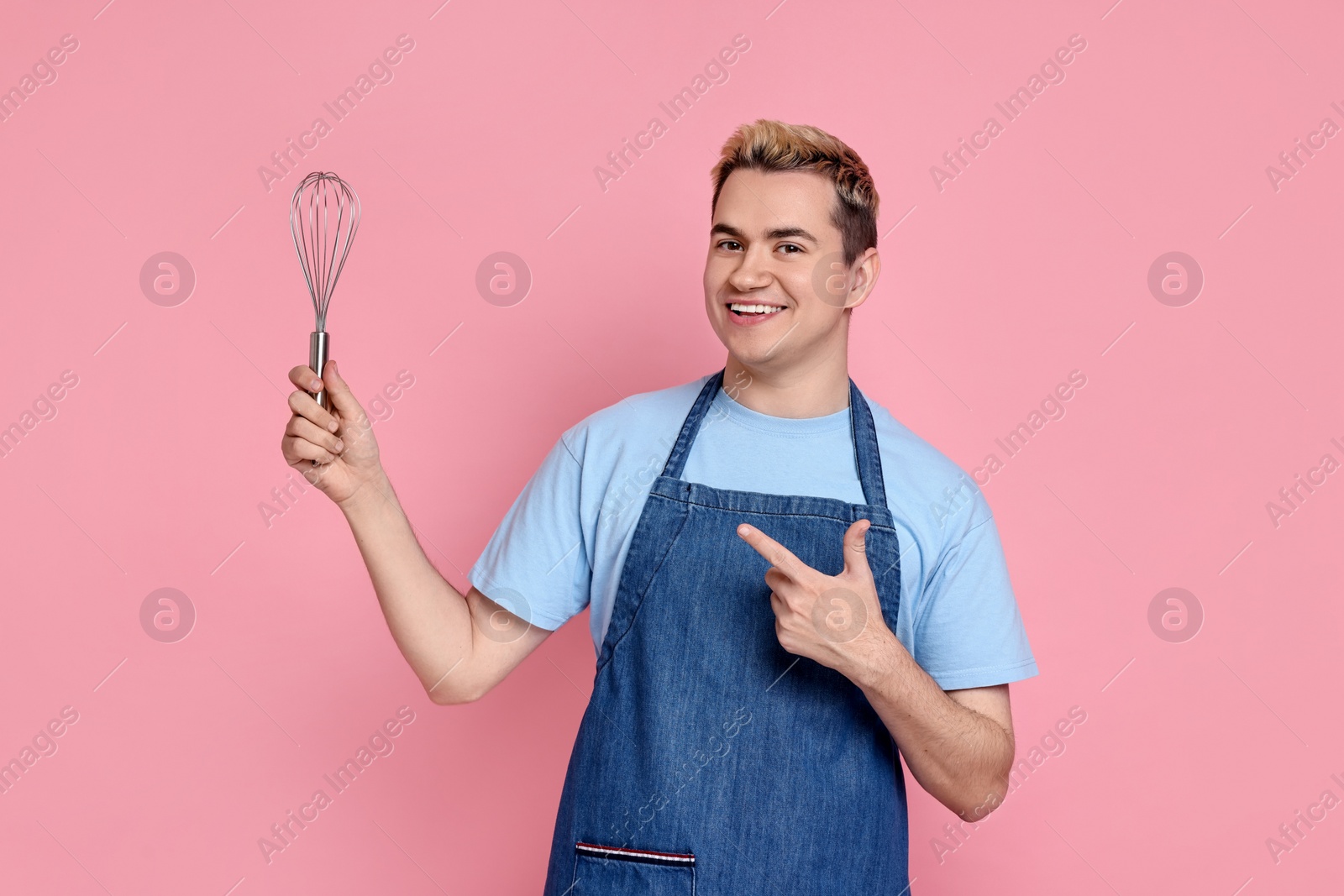 Photo of Portrait of happy confectioner holding whisk on pink background