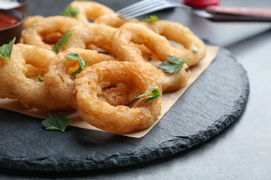 Photo of Fried onion rings served on slate plate, closeup