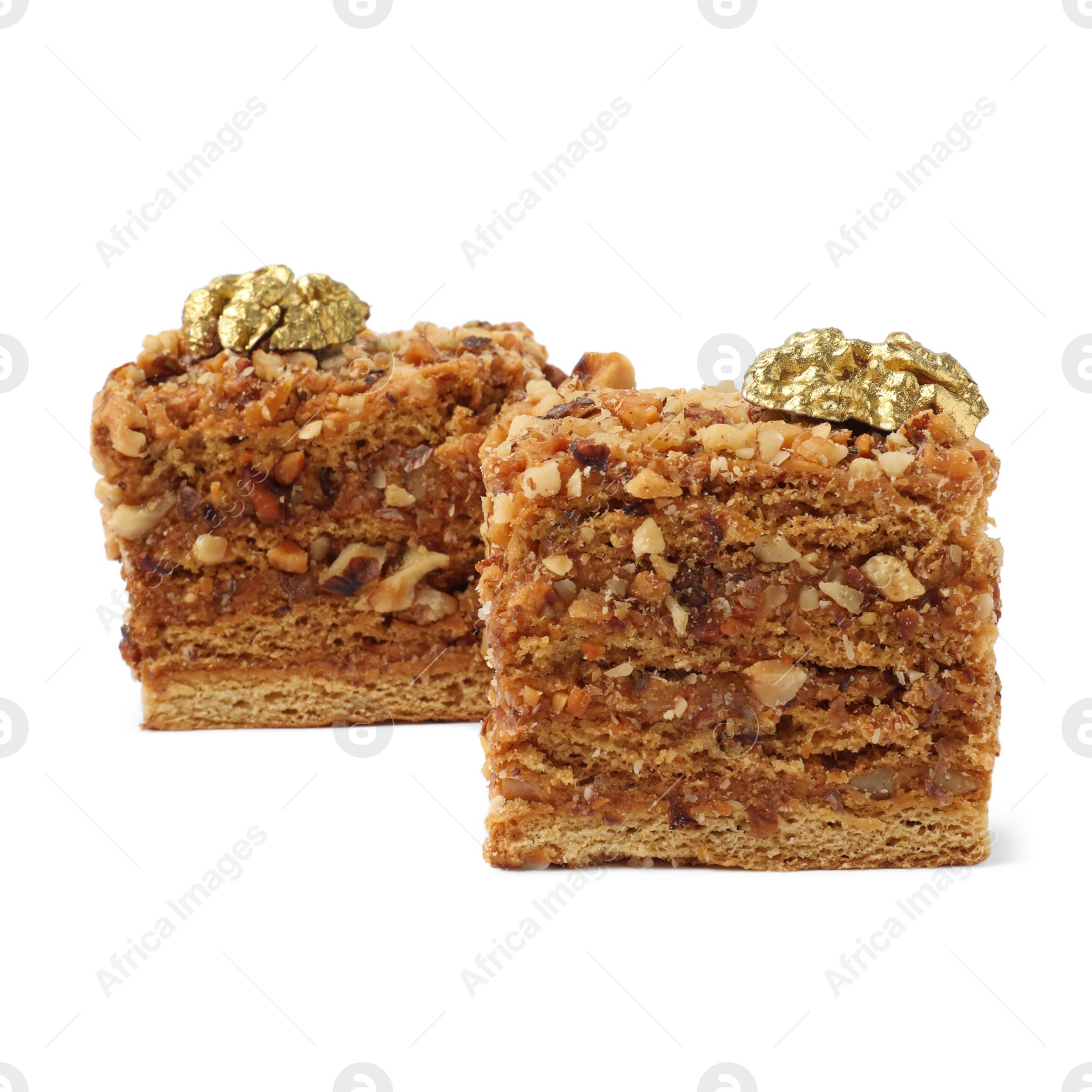 Photo of Pieces of layered honey cake with walnuts on white background