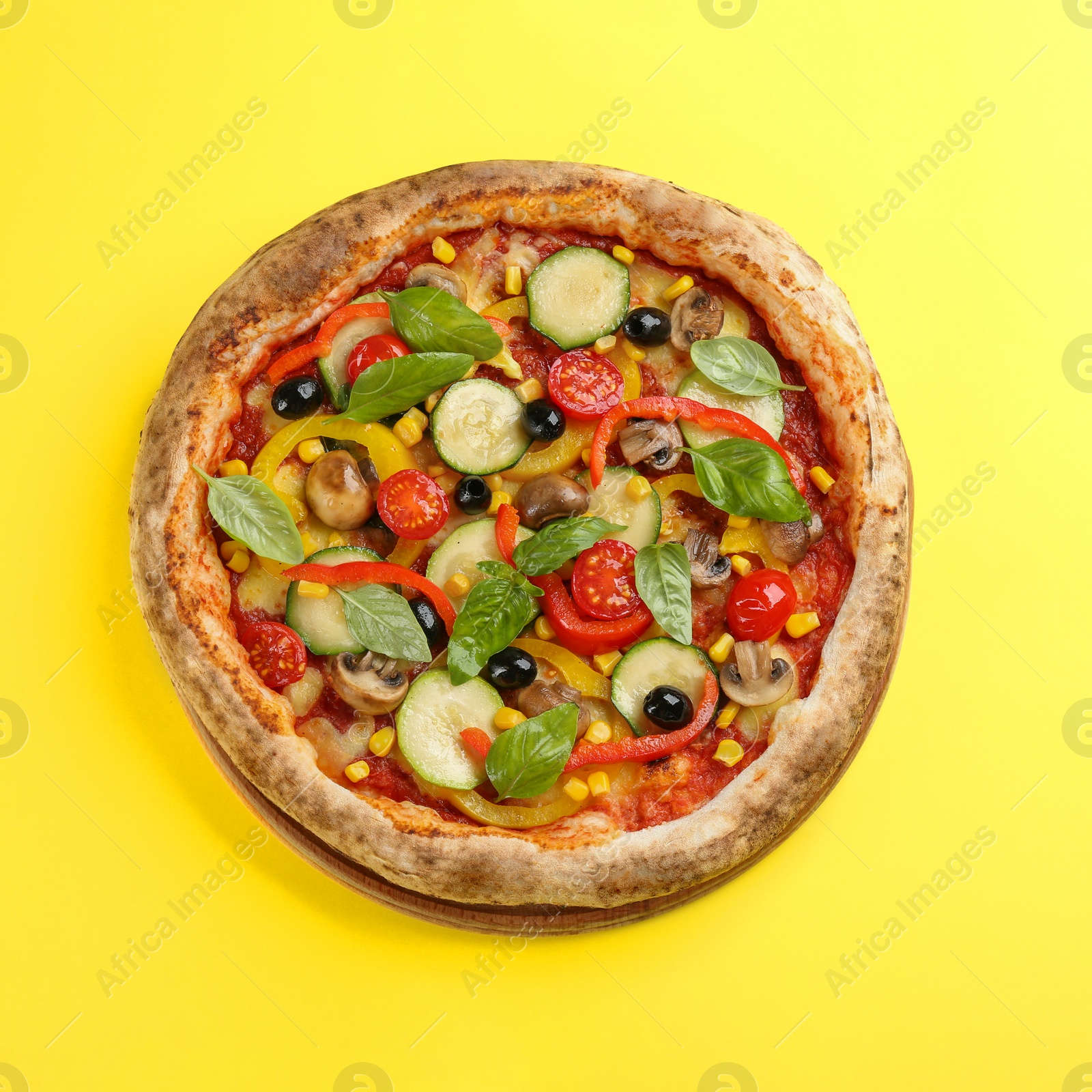 Photo of Delicious hot vegetable pizza on yellow background, top view