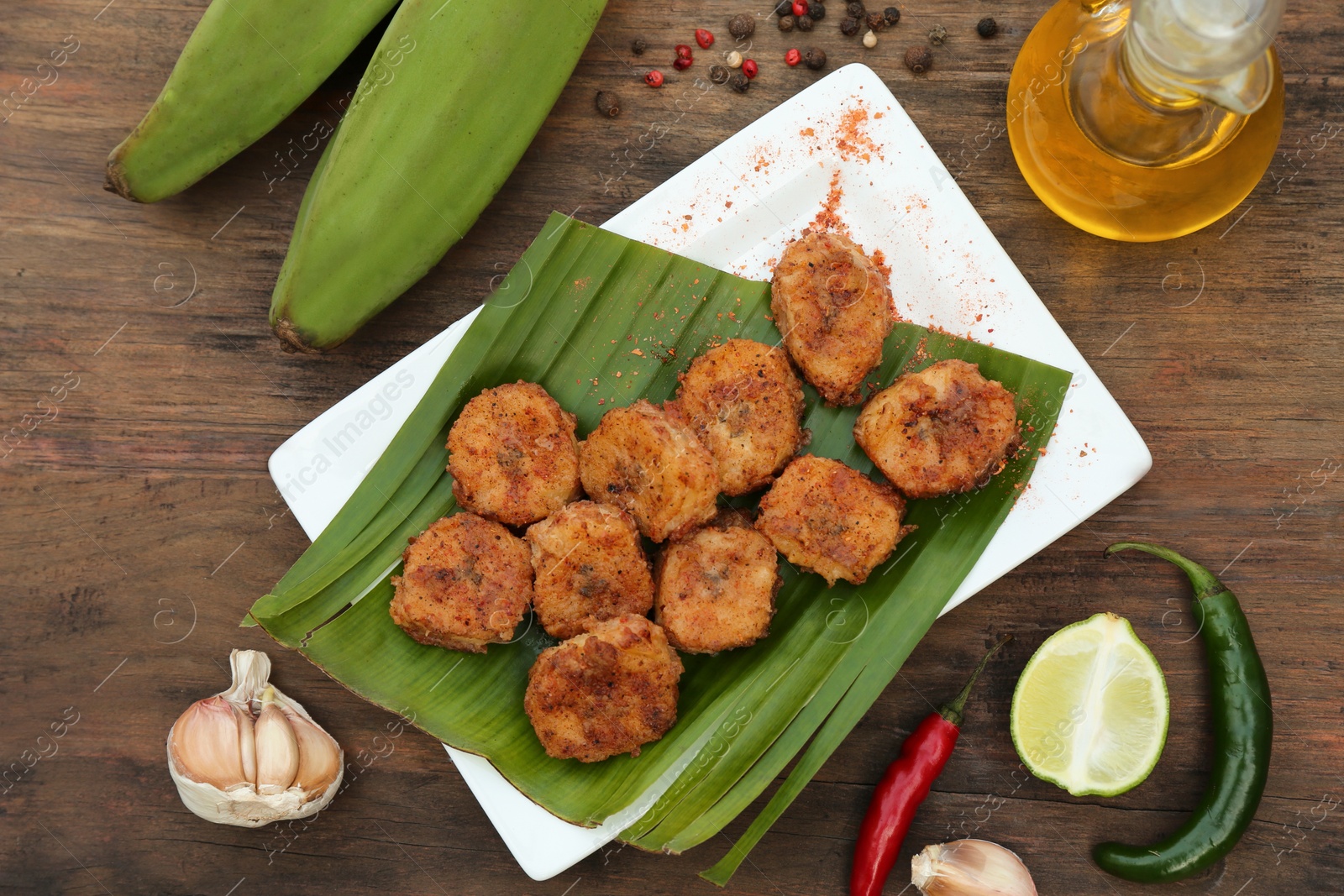 Photo of Delicious fried bananas, fresh fruits and different peppers on wooden table, flat lay