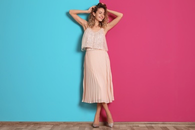 Photo of Young woman with beautiful long legs in stylish outfit near color wall