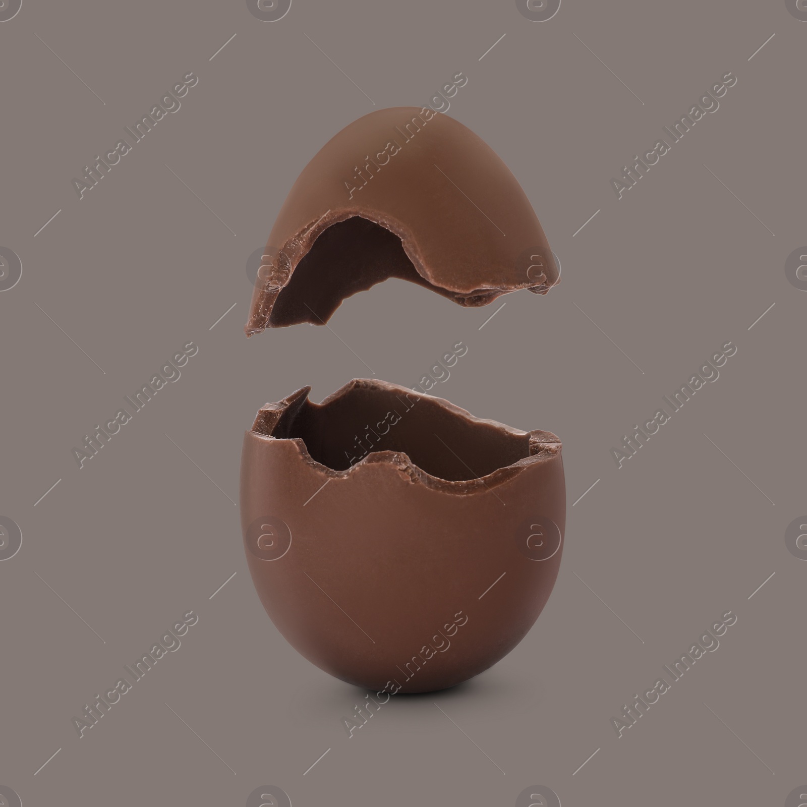 Image of Broken milk chocolate egg on grey background