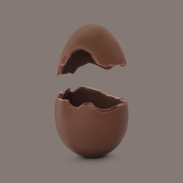 Broken milk chocolate egg on grey background