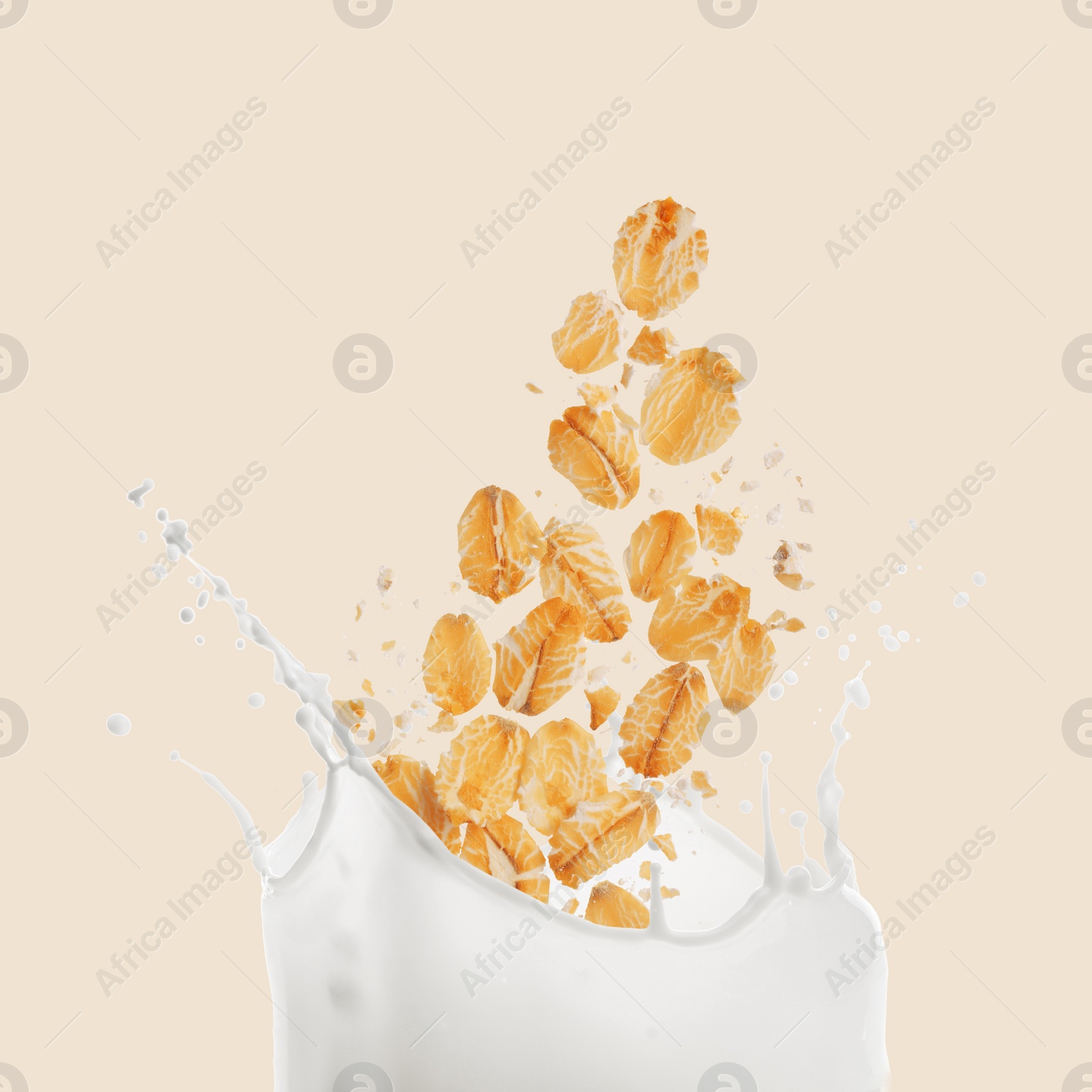 Image of Rolled oats falling into splashing milk on beige background