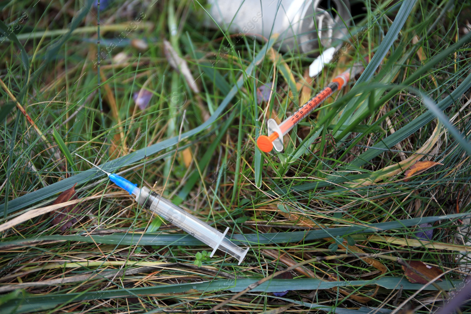 Photo of Disposable syringes with needles on green grass outdoors