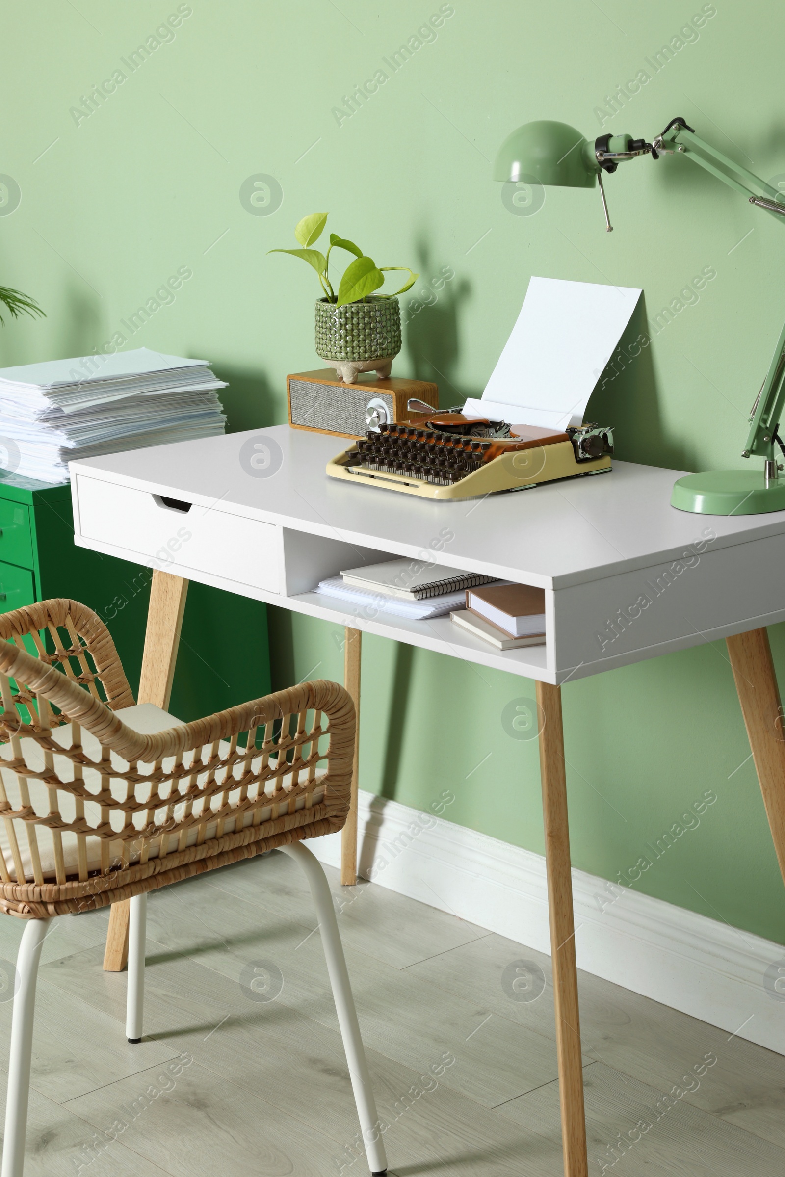 Photo of Writer's workplace with typewriter on wooden desk near pale green wall in room