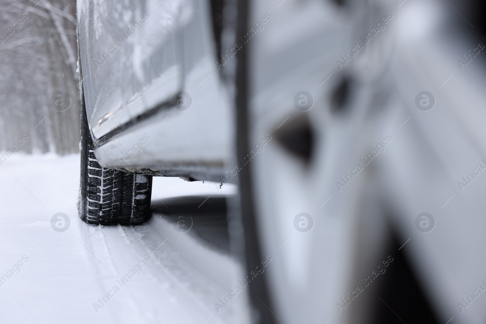 Photo of Car with winter tires on snowy road outdoors, closeup. Space for text