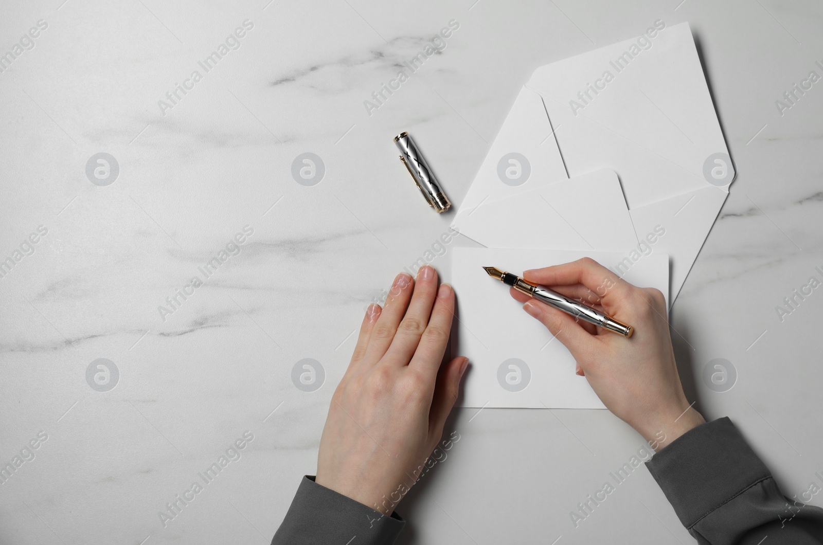 Photo of Woman writing letter at marble table, top view. Space for text