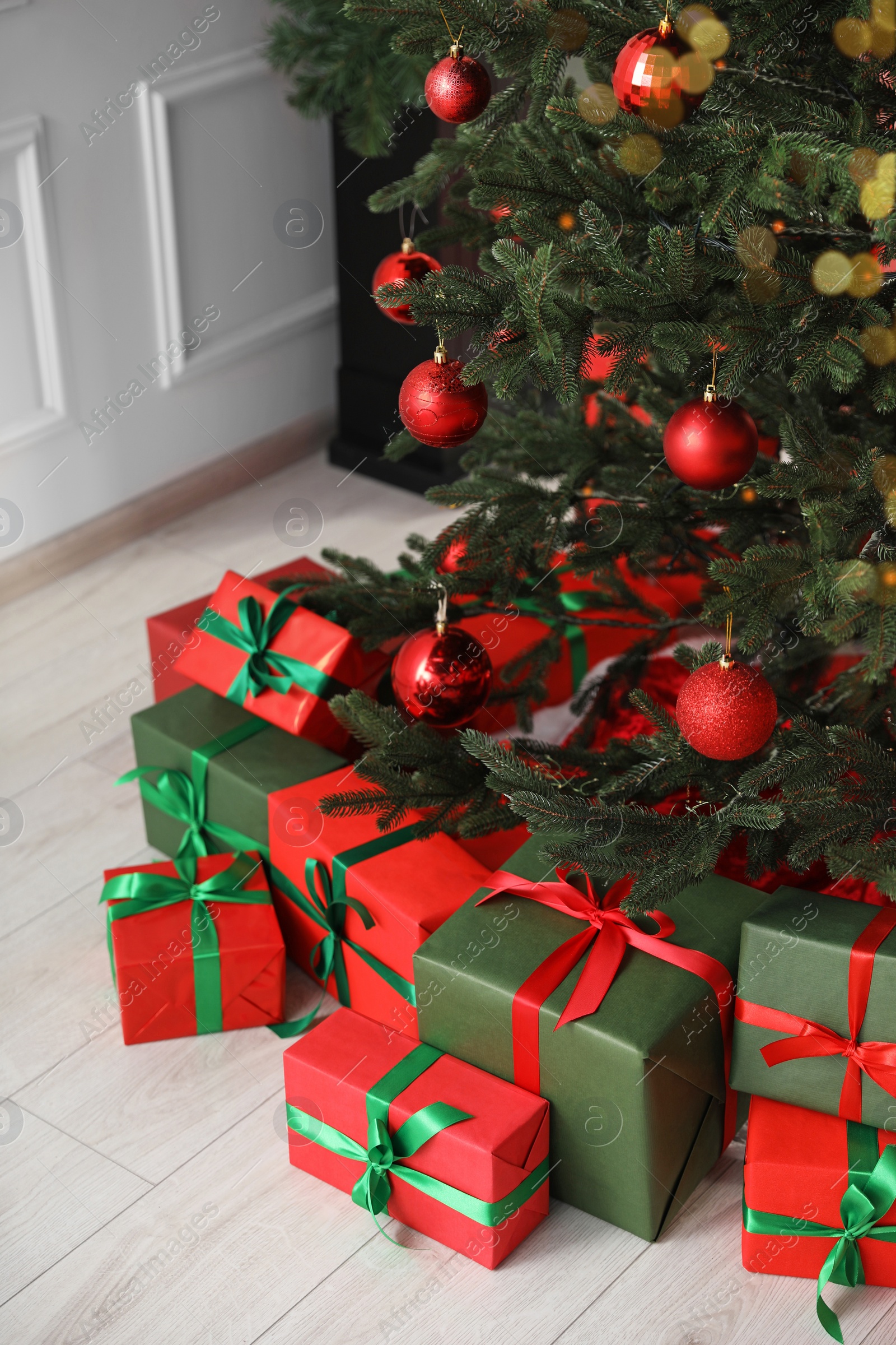 Photo of Beautifully wrapped gift boxes under Christmas tree indoors