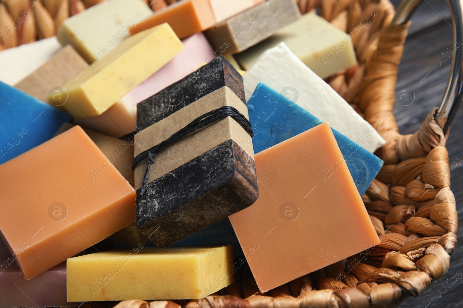 Photo of Many different handmade soap bars in wicker basket, closeup