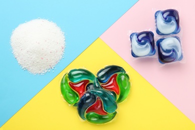Photo of Different laundry capsules and washing powder on color background, flat lay