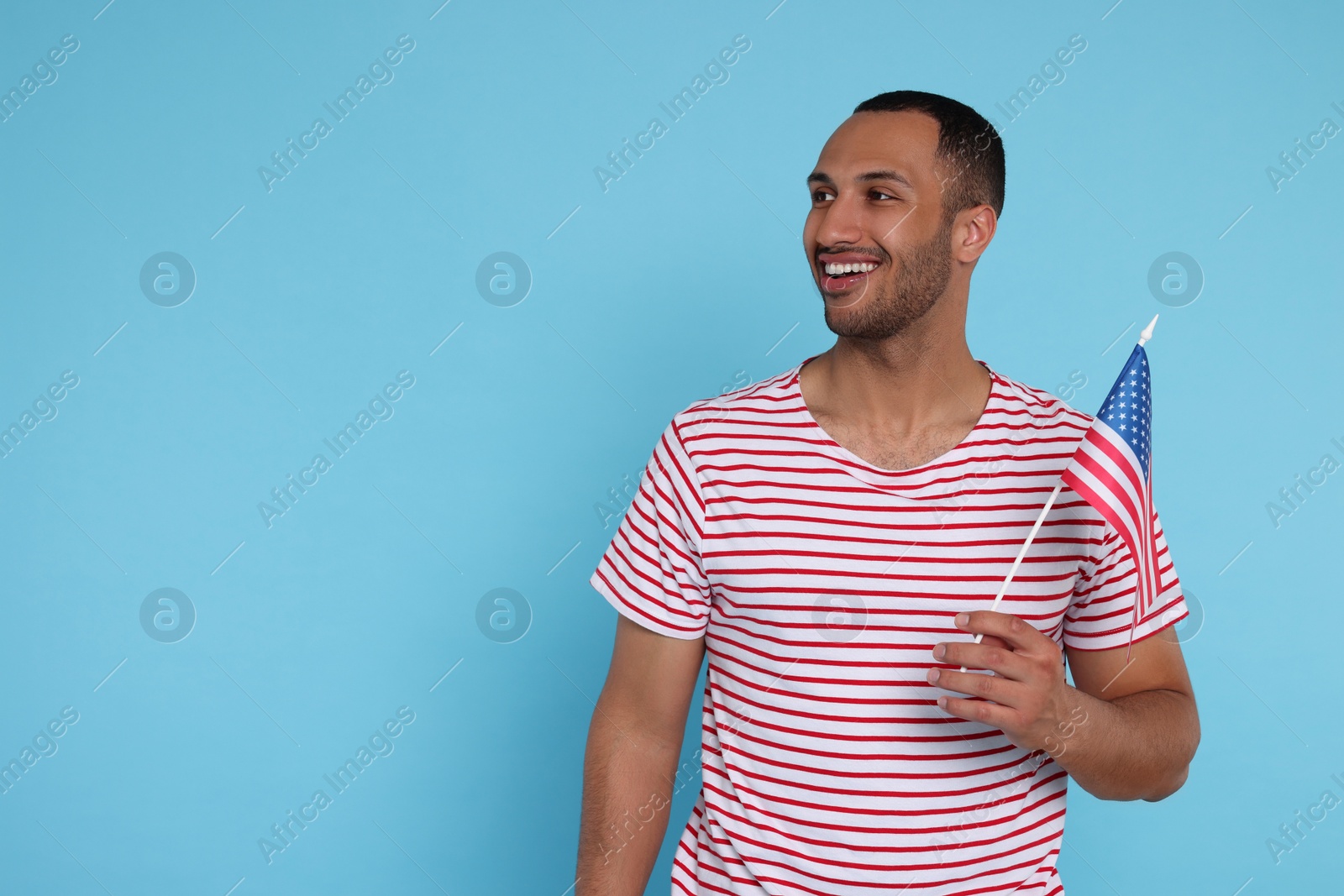 Photo of 4th of July - Independence Day of USA. Happy man with American flag on light blue background, space for text