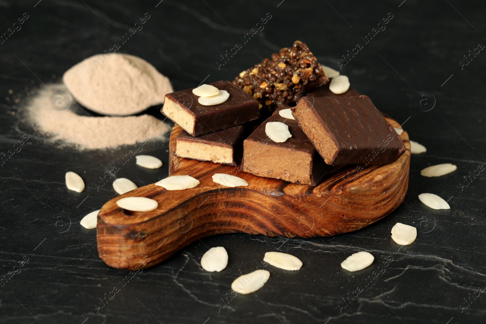 Photo of Different energy bars, almond flakes and protein powder on black table