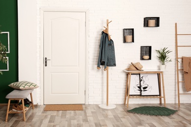 Photo of Stylish hallway interior with shoe storage bench, hanger stand and table