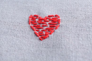 Photo of Embroidered red heart on gray cloth, closeup