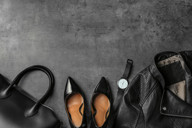 Photo of Leather jacket, shoes, bag and wristwatch on grey stone table, flat lay. Space for text