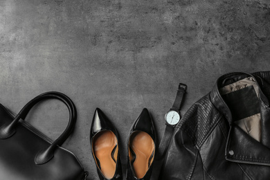 Leather jacket, shoes, bag and wristwatch on grey stone table, flat lay. Space for text