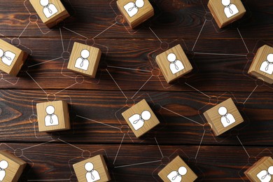 Teamwork. Cubes with human icons linked together symbolizing cooperation on wooden background, top view