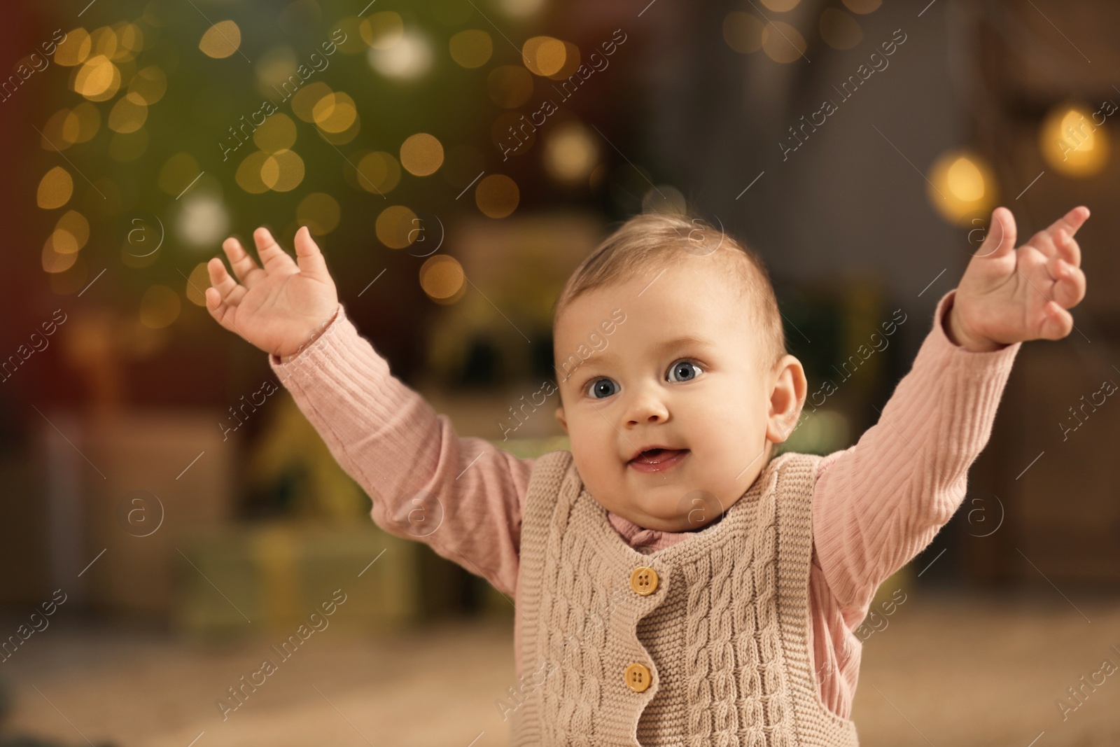 Photo of Cute little baby and blurred Christmas lights on background. Winter holiday