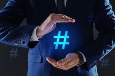 Image of Hashtag concept. Man holding sign on dark background, closeup