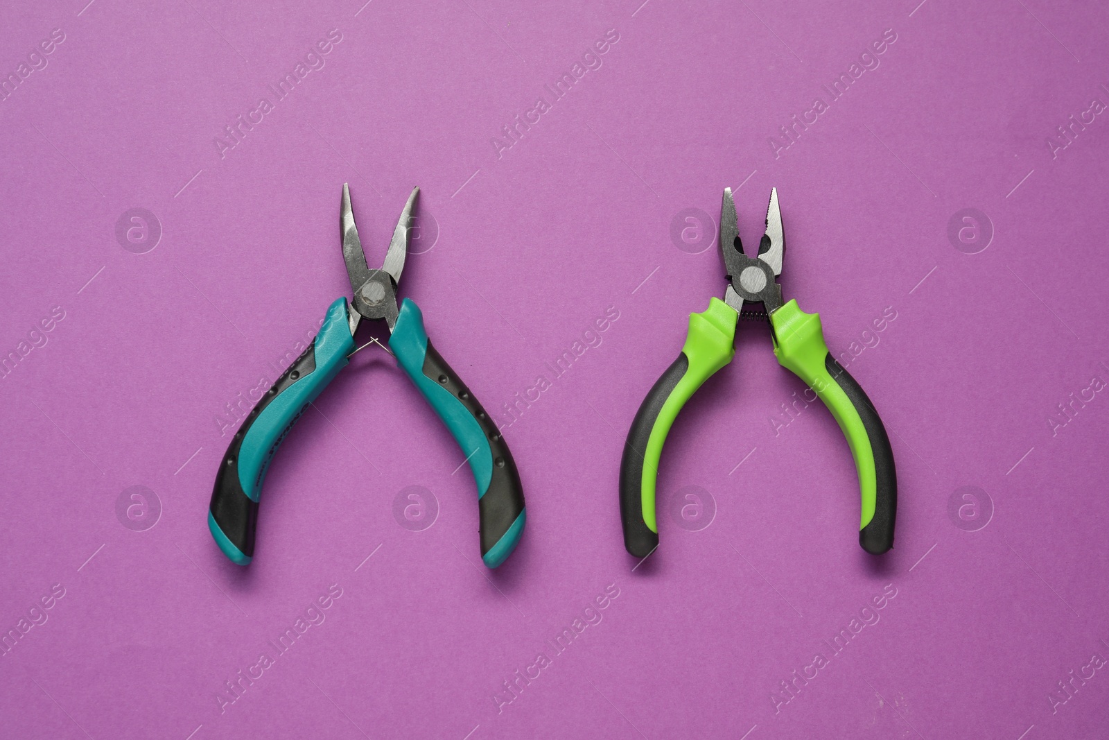 Photo of Two pliers on purple background, flat lay