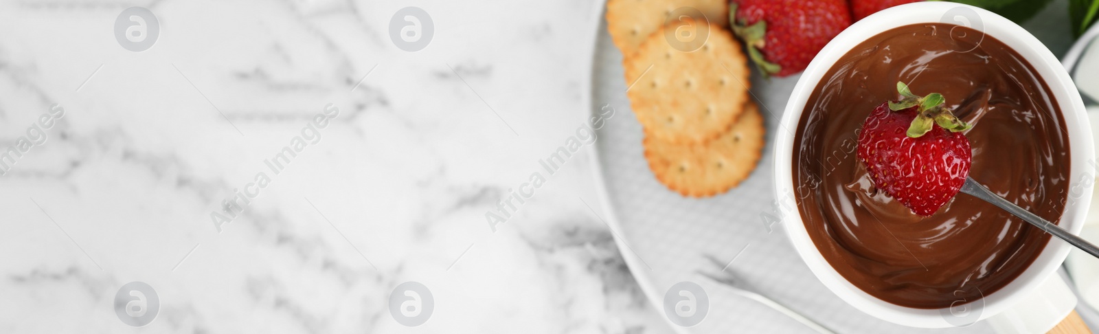 Image of Fondue pot with chocolate and strawberry on white marble table, top view with space for text. Banner design