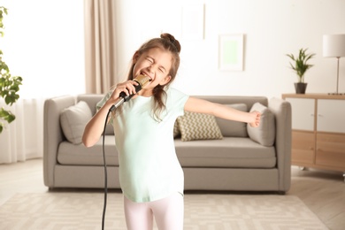 Cute funny girl with microphone in living room