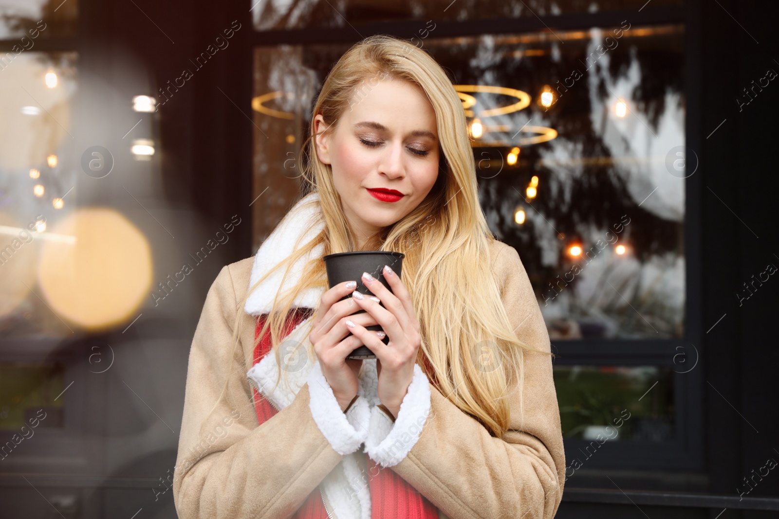 Photo of Young woman with hot drink at winter fair. Christmas celebration