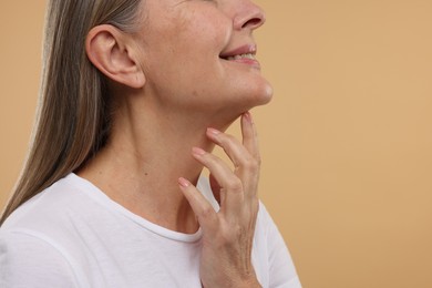 Photo of Mature woman with healthy skin on beige background, closeup. Space for text