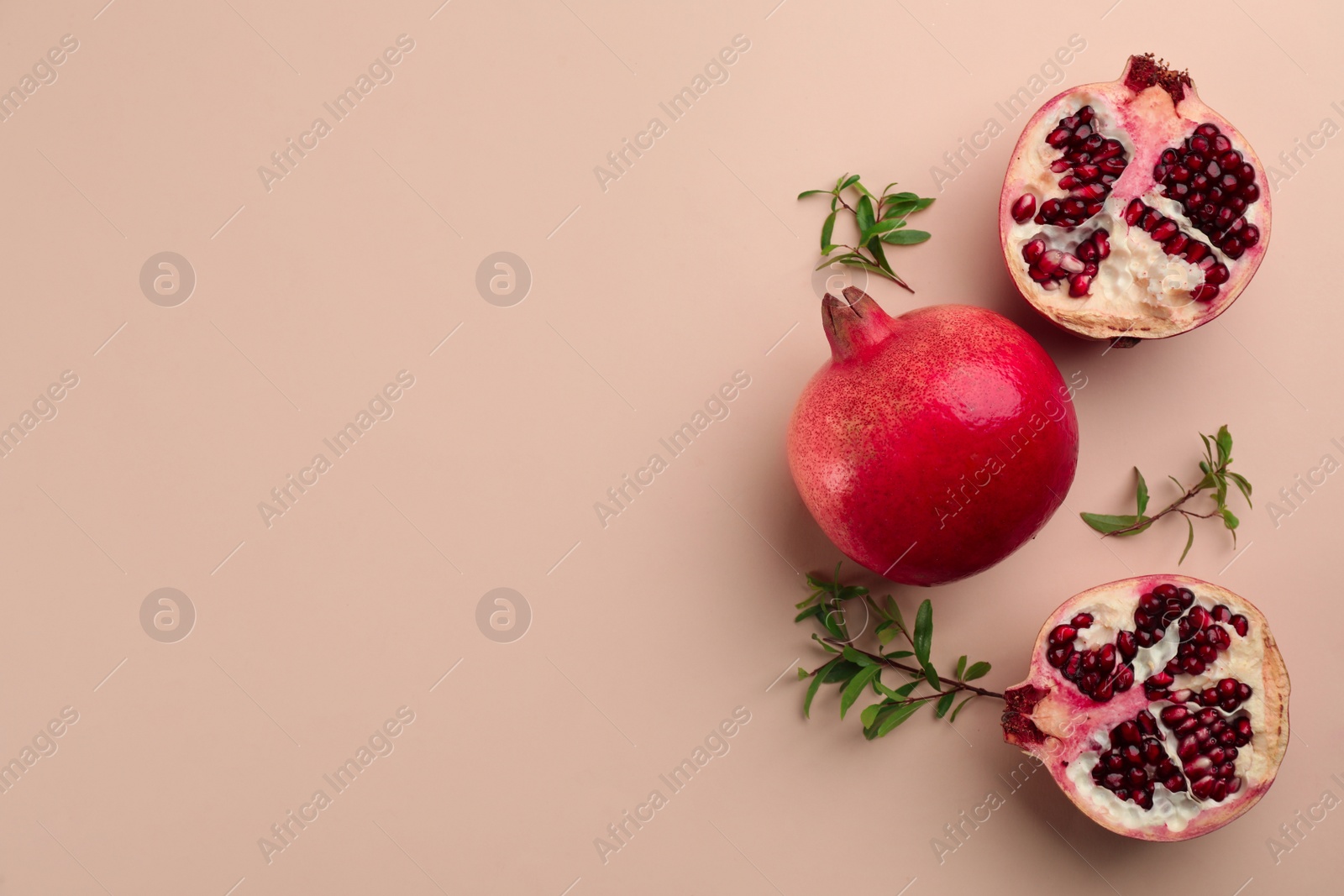 Photo of Flat lay composition with ripe pomegranates on beige background. Space for text