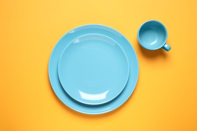 New ceramic dishware on yellow background, flat lay