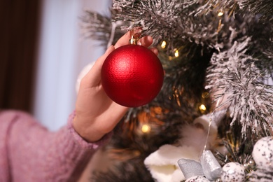 Woman decorating Christmas tree at home, closeup