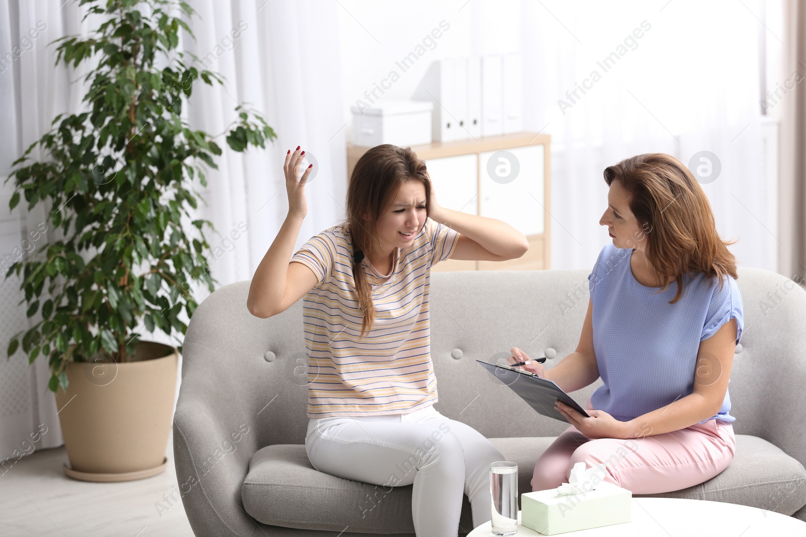 Photo of Psychotherapist working with teenage girl in office